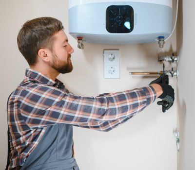 Professional plumber checking a boiler and pipes, boiler service concept.